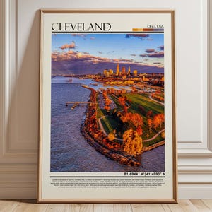 May include: Framed print featuring a scenic aerial view of Cleveland, Ohio, USA. The image showcases the city skyline, a river, and a park with autumn foliage. The print includes the city name and coordinates.