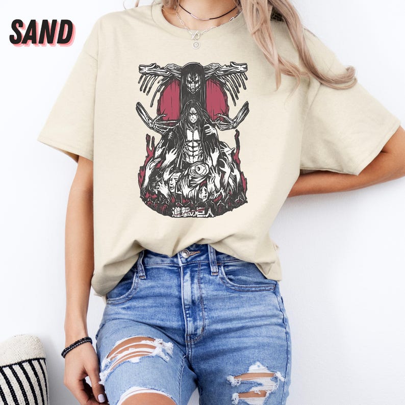 May include: A beige t-shirt with a black and white graphic print of a character from the anime Attack on Titan. The graphic features the character with a red background and the text "進撃の巨人" in Japanese.