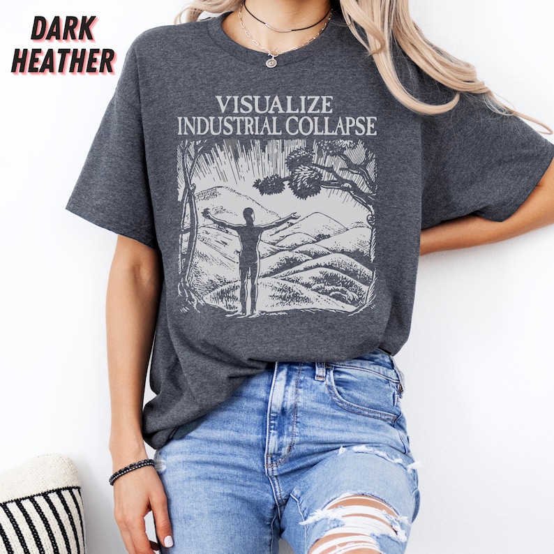Peut inclure: Un t-shirt gris chin&eacute; fonc&eacute; avec le texte "Visualize Industrial Collapse" imprim&eacute; sur le devant. Le texte est en blanc et est entour&eacute; d'une illustration en noir et blanc d'une personne debout sur une colline, les bras tendus.