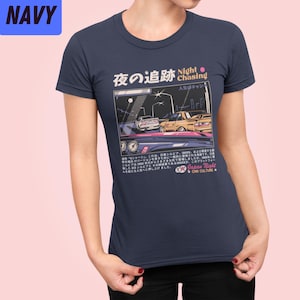 May include: A navy blue t-shirt with a graphic of two cars driving at night. The graphic is in a retro video game style. The text on the shirt reads "Night Chasing" and "Japan Night Car Culture".