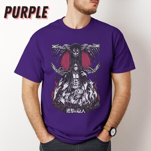 May include: Purple t-shirt with a graphic print of a character from the anime "Attack on Titan". The character is surrounded by other characters and the text "進撃の巨人" is printed below the graphic.