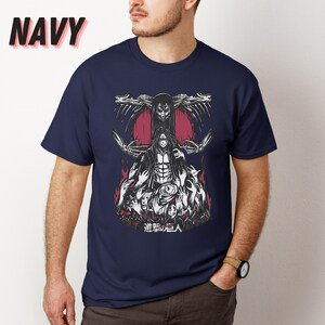 May include: A navy blue t-shirt with a graphic print of a character from the anime Attack on Titan. The character is surrounded by other characters and the text "進撃の巨人" is printed below the graphic.