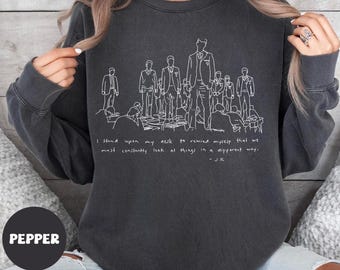 May include: Dark gray sweatshirt with a white line drawing of a group of people and the quote "I stand upon my desk to remind myself that we must constantly look at things in a different way." The word "PEPPER" is in a circle at the bottom.