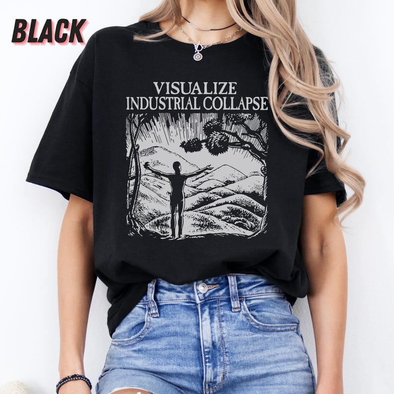 Peut inclure: Un t-shirt noir avec un imprim&eacute; graphique blanc d'une personne debout, les bras tendus devant une cha&icirc;ne de montagnes. Le texte "VISUALIZE INDUSTRIAL COLLAPSE" est imprim&eacute; au-dessus du graphique.