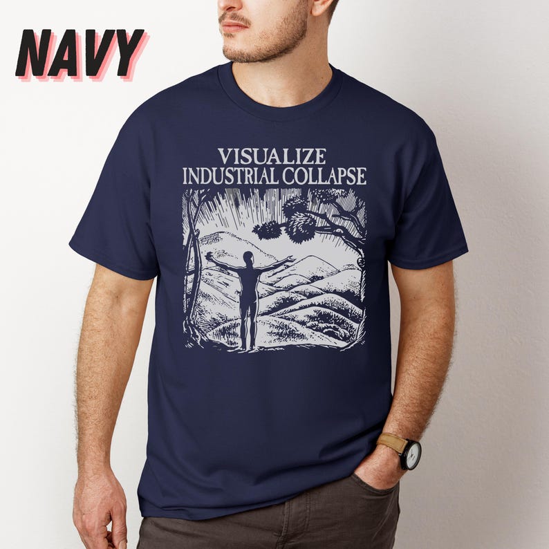 Peut inclure: Un t-shirt bleu marine avec un imprim&eacute; graphique blanc d'une personne debout, les bras tendus devant une cha&icirc;ne de montagnes. Le texte "VISUALIZE INDUSTRIAL COLLAPSE" est imprim&eacute; au-dessus du graphique.