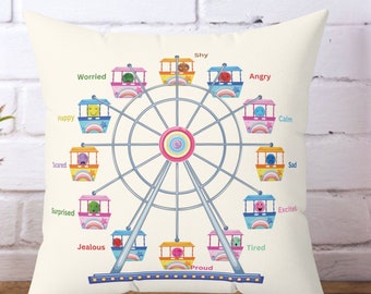 May include: A white pillow with a colorful Ferris wheel design. The Ferris wheel has 12 cars, each with a different emotion on the face of the person inside. The emotions are: Happy, Worried, Shy, Angry, Calm, Sad, Excited, Tired, Jealous, Scared, Surprised, and Proud.