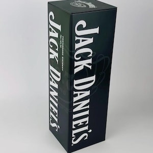 Puede incluir: Una caja negra con las palabras "Jack Daniel's" en letras blancas. La caja es para whisky de Tennessee.