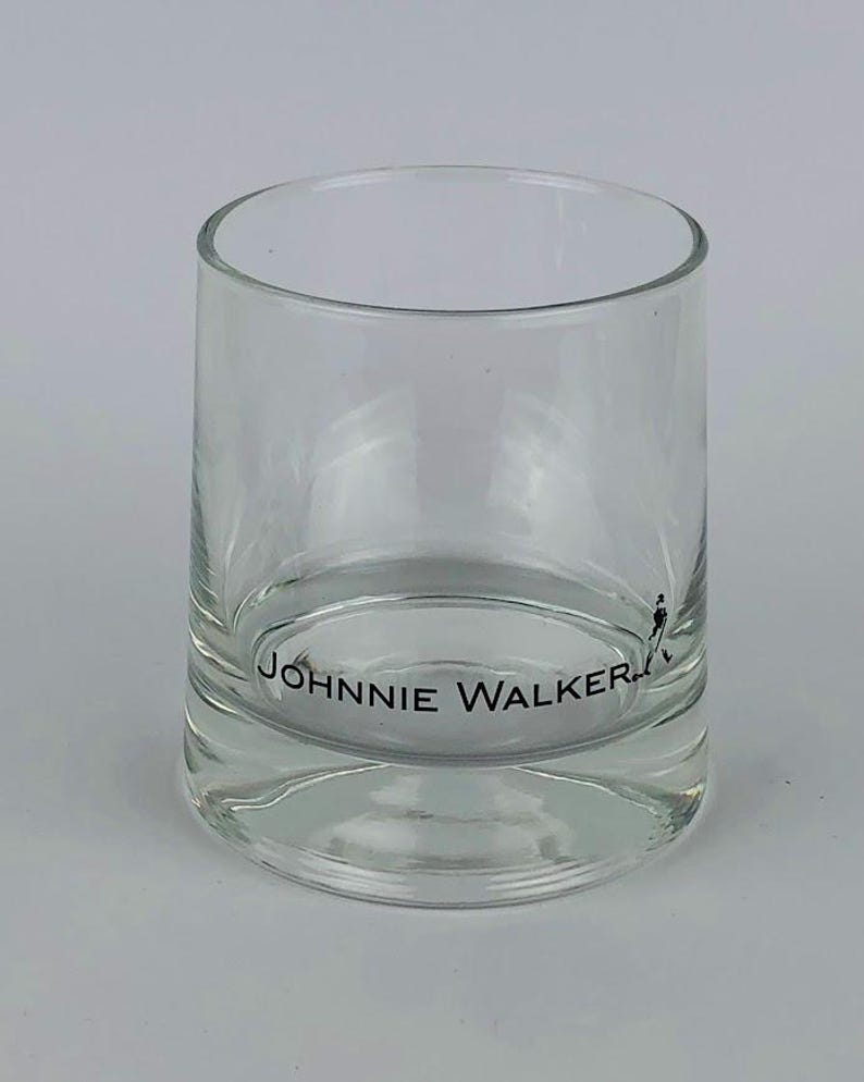 May include: A clear glass tumbler with the words "JOHNNIE WALKER" printed on the bottom.