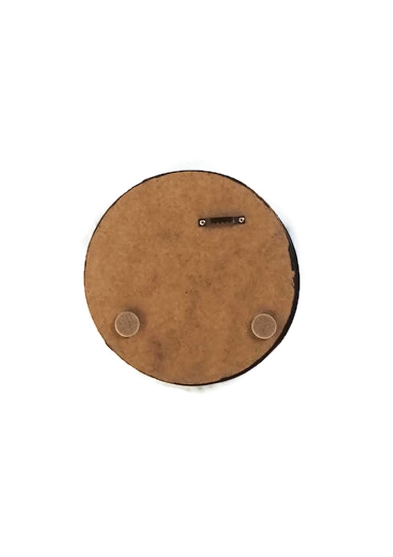 May include: A round, brown wooden plaque with a black edge. The back of the plaque features a metal hanger and two small, round, tan-colored pads. The plaque is set against a white background.