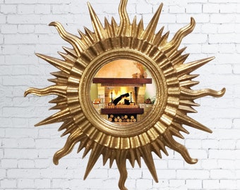 May include: A gold sunburst mirror with a round mirror reflecting a fireplace with a fire burning inside. The mirror is hanging on a white brick wall.