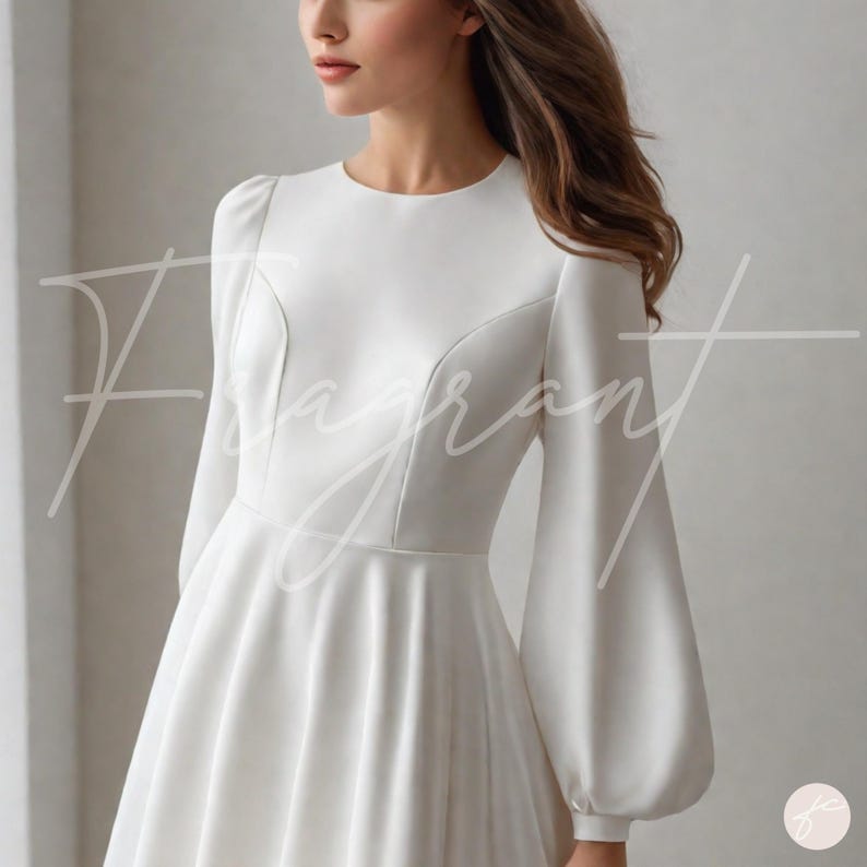 May include: A white wedding dress with long, voluminous sleeves and a fitted bodice. The dress features a round neckline and a flared skirt. The word "Fragrant" is written in cursive across the front of the dress.