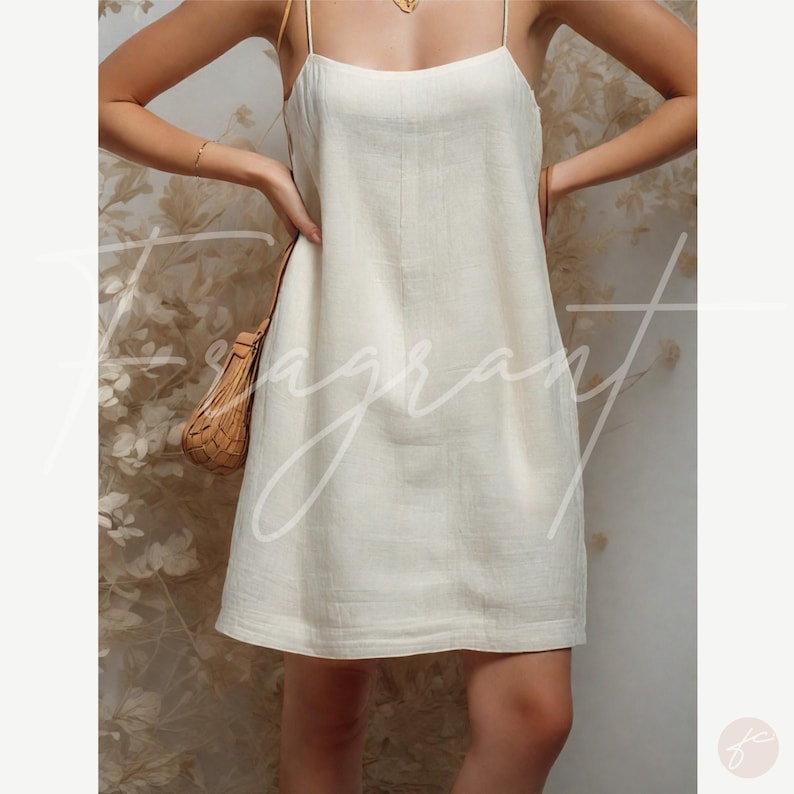 May include: A white linen slip dress with thin straps. The dress has a simple, relaxed fit and a slightly A-line silhouette.
