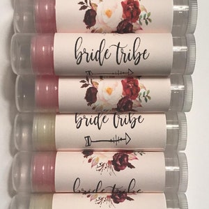 May include: A stack of eight clear tubes with pink and white labels. The labels feature a floral design with burgundy and pink flowers and the text "bride tribe".