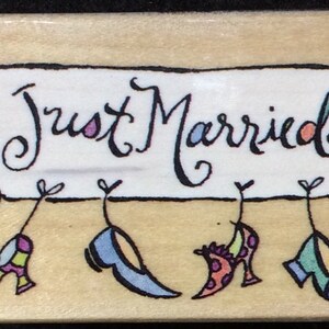 May include: A white banner with the text "Just Married" in black cursive writing. Four colorful shoes hang from the banner.