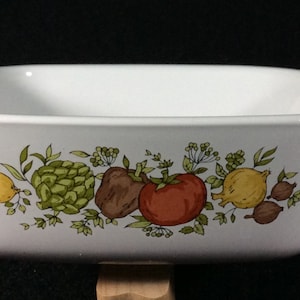 Puede incluir: Plato para hornear rectangular blanco con un diseño floral que presenta limones, alcachofas, tomates y otras verduras en tonos de verde, amarillo, rojo y marrón.