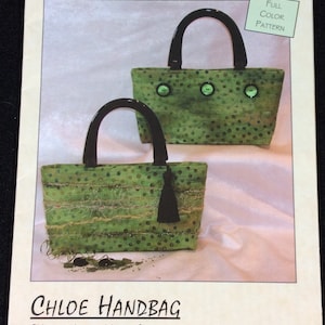 May include: A sewing pattern for a green and black handbag with a polka dot design. The pattern is called "Chloe Handbag" and is from Lazy Girl Designs. The pattern includes instructions for making a handbag that is 1/2 inch wide by 5 3/4 inches high.
