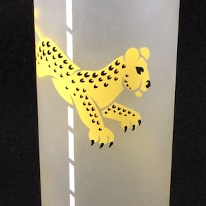 May include: A frosted glass with a yellow cheetah design on a white pole. The glass has a black and white wavy design at the top and a black and white polka dot design at the bottom.