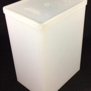 May include: A white plastic rectangular container with a lid. The container is empty.