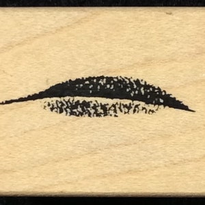 Puede incluir: Un sello de goma negro con un diseño de una sola pestaña negra estilizada.