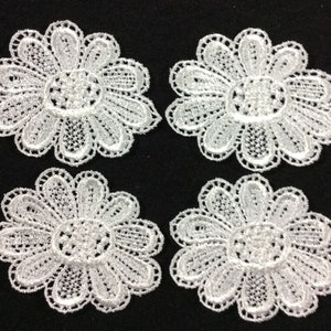 May include: Four white lace flower appliques with a delicate, intricate design. Each applique is approximately 2 inches in diameter.