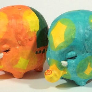 May include: Two ceramic elephant figurines with colorful geometric patterns. One is orange, yellow, and green, and the other is blue, yellow, and green.