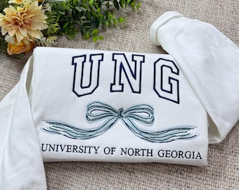 May include: White sweatshirt with blue embroidered lettering that reads "UNG UNIVERSITY OF NORTH GEORGIA" and a blue embroidered bow.