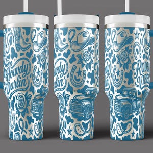 May include: A set of three insulated travel mugs with a blue and white cowboy-themed design. The design includes cowboy boots, hats, roses, horseshoes, and vintage trucks. The mugs have blue handles and lids, and the text "Howdy Darlin'" and "Rodeo Vibes" are visible.