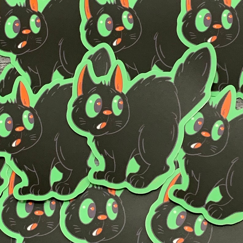 Peut inclure: Un ensemble d'autocollants de chats noirs avec des yeux verts et une expression surprise. Les autocollants sont sur un fond vert.