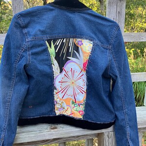 May include: A blue denim jacket with a black velvet collar and a colorful floral patch on the back.