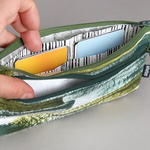 May include: A green and white zippered pouch with a leafy pattern. The pouch is open and has three cards inside. The pouch has a "WONDERLY" label on the side.