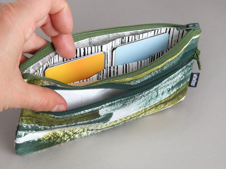 May include: A green and white zippered pouch with a leafy pattern. The pouch is open and has three cards inside. The pouch has a "WONDERLY" label on the side.