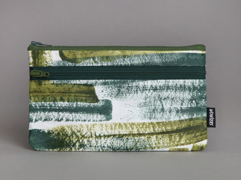 May include: A green and white double zippered pencil case with a brushstroke pattern and the word "WOWERS" printed on the side.