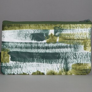 May include: A green zippered pouch with a white and green abstract brushstroke pattern. The pouch has a black label with the word "WOWSER" printed on it.