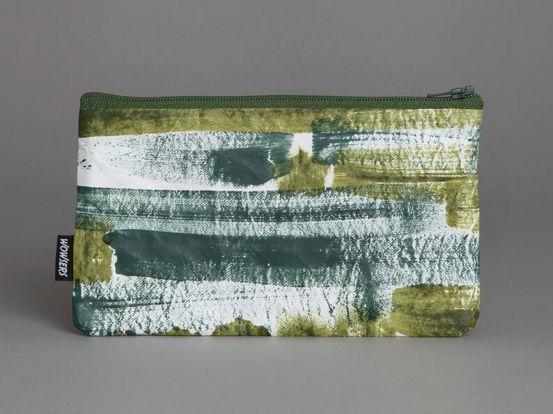 May include: A green zippered pouch with a white and green abstract brushstroke pattern. The pouch has a black label with the word "WOWSER" printed on it.