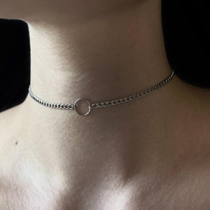 May include: A silver chain choker necklace with a circular pendant.
