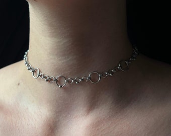 May include: A silver chain choker necklace with multiple round links and a small bead accent.