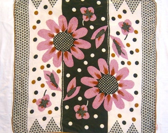 May include: A square scarf with a floral design. The scarf features large pink flowers with black centers and leaves, set against a black and white polka-dotted background. The border has a geometric pattern with a brown trim.
