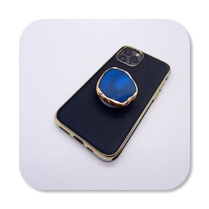 May include: A black phone case with a gold trim and a blue agate phone ring holder.