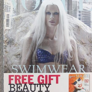 May include: A magazine cover for Vogue Italia featuring a model with platinum blonde hair wearing a blue and black swimsuit. The cover text reads "Swimwear" and "Free Gift Beauty in Vogue". A smaller magazine cover for Vogue Beauty In is featured in the bottom right corner with the text "Hot Season" and "Monica Bellucci inedita".