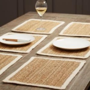 May include: Set of six natural woven placemats with white trim. The placemats are made from a natural material and have a rustic look.