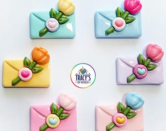 May include: Flower envelope cover minders in various pastel colors. Each minder features a small envelope with a flower and heart design. Colors include yellow, pink, blue, and lavender. The text "Tracy's DP World" is in the center.