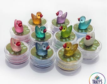 May include: A collection of colorful duck figurines, each perched on a lily pad within a clear container. The ducks come in various colors, including pink, yellow, green, and blue. Text on the image reads "LILYPAD - DUCKS" and "WET THE SPONGE - WORKS WITH WAX OR PUTTY KEEPS ABS FROM STICKING."