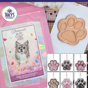 May include: A pink package with the text "Diamonds in the Ruff 2026 Event Set" and "Peanut Butter Scented Putty." Includes a paw print-shaped item and six paw print keychains with decorative gems.