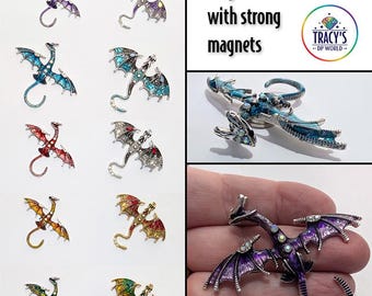 May include: A collection of dragon-shaped cover minders in various colors, including purple, blue, red, and gold. The text reads "PREMIUM DRAGON COVER MINDERS" and "Large cover minder with strong magnets". Available in 2 styles with 10 different dragon designs.