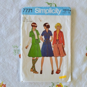 May include: A vintage Simplicity sewing pattern packet, showing illustrations of three outfits: a green skirt suit, a blue denim dress, and a red jacket with a striped skirt. The packet has the number 7771 and the Simplicity logo.