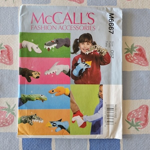 May include: A McCall's M6667 sewing pattern envelope for fashion accessories featuring illustrations of various animal-themed hand puppets. The front displays multiple colorful puppet designs, including a shark, leopard, and monkey, with text labels.