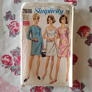 May include: Vintage Simplicity sewing pattern 7696 for a dress. The pattern is for half-sizes 18 1/2 - 22 1/2, bust 41. The pattern features three women wearing different styles of dresses. The pattern is printed on a white background with blue and red text.