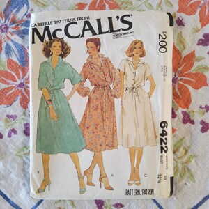 Könnte beinhalten: Ein Vintage-Schnittmuster von McCall's für ein Kleid. Das Schnittmuster ist für Größe 10 mit einem Brustumfang von 82 cm. Das Schnittmuster ist für ein Kleid mit einer Schleife in der Taille und einem Knopfleisten vorne. Das Schnittmuster stammt aus der Carefree Patterns-Kollektion. Das Schnittmuster kostet 2,00 €.