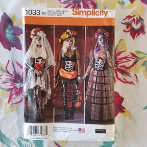 Op de afbeelding: Een Simplicity-naaipatroon voor een Day of the Dead-kostuum. Het patroon is voor maten 14-22 en bevat drie verschillende kostuumopties. De patroonhoes toont drie vrouwen die de kostuums dragen, elk met een andere stijl van jurk en make-up. Het patroon is getiteld "1033" en is voor een "Day of the Dead"-kostuum.