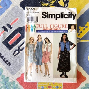 May include: A Simplicity sewing pattern titled "7092" for full figure solutions. The pattern features illustrations of dresses and a denim vest. The text on the pattern includes "Full Figure Solutions" and "The Hoax System to Flatter Your Body Type."